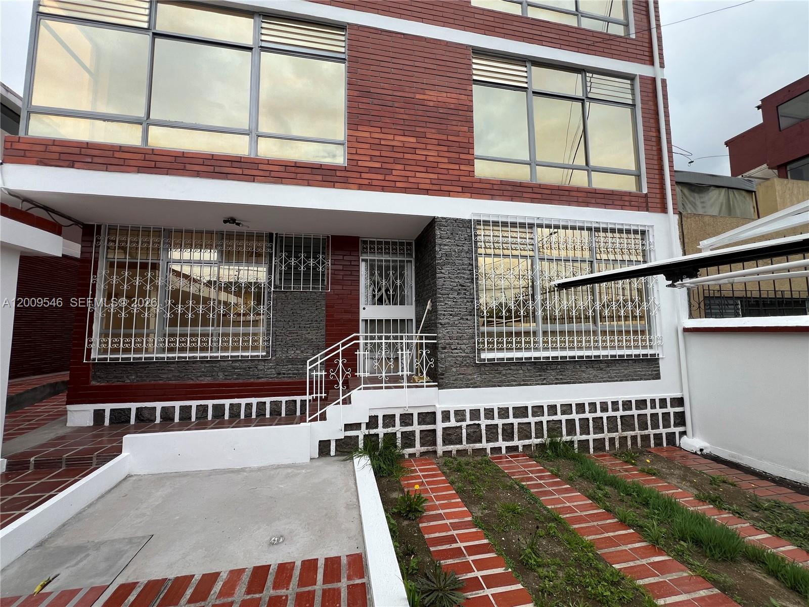 The exterior of a multi-story brick building features large windows with white security grilles — N35-95 Calle Manuela Sáenz, FL, FL