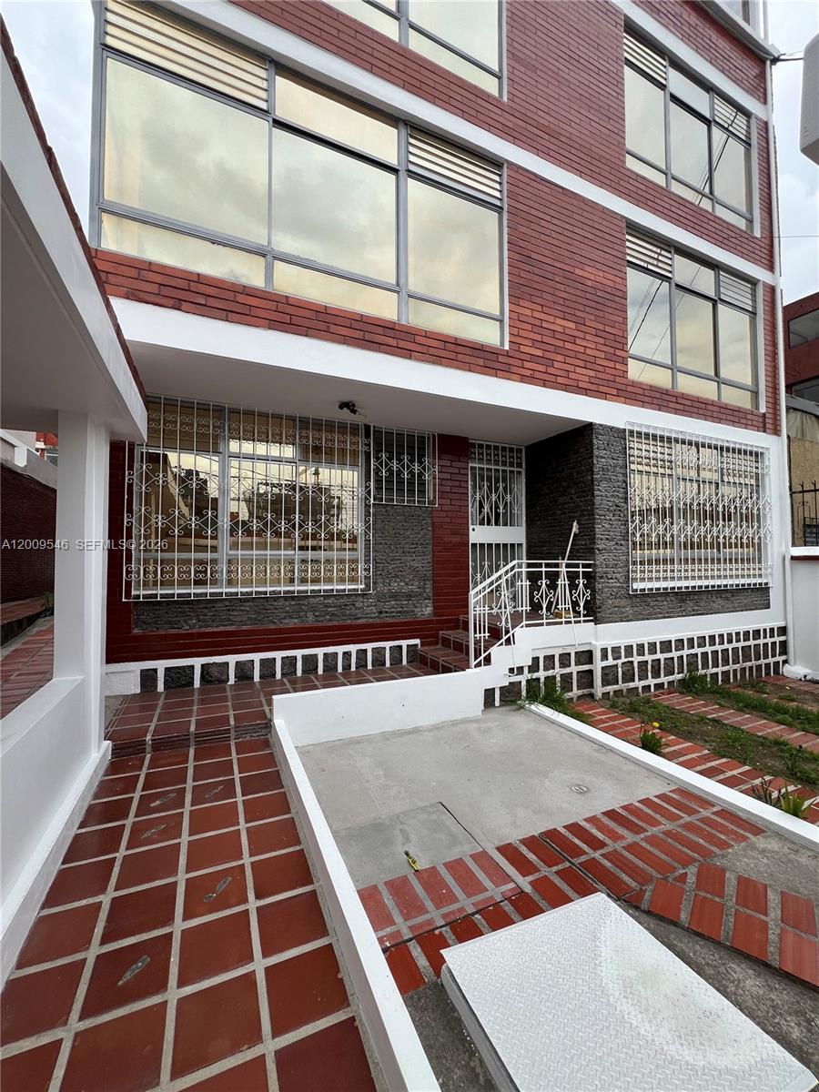 The exterior of a multi-story brick building features large windows with white security grilles — N35-95 Calle Manuela Sáenz, FL, FL