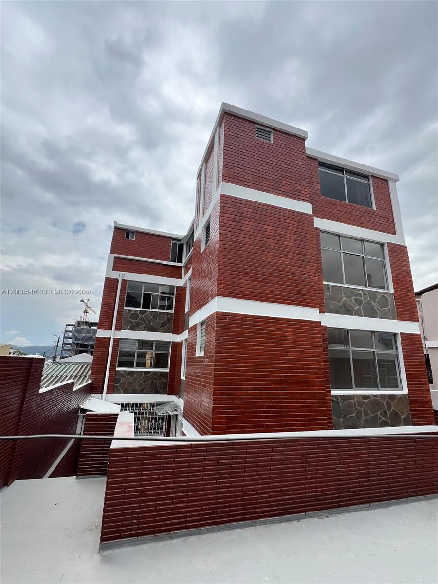 A multi-story building features red brick siding, stone accents, and several rectangular windows — N35-95 Calle Manuela Sáenz, FL, FL