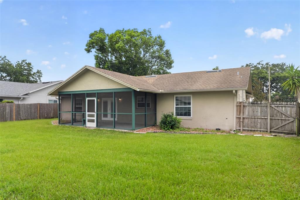The back exterior of a single-story house features a screened-in porch and a fenced yard — 854 N JERICO DRIVE, CASSELBERRY, FL