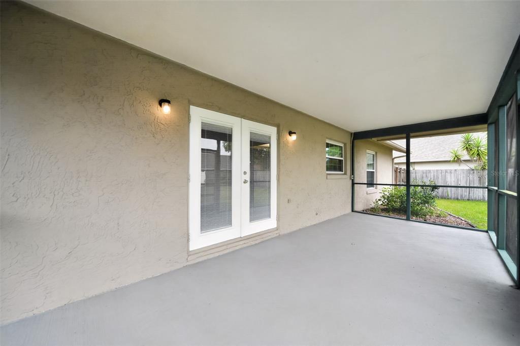 A covered patio with a gray concrete floor, beige stucco walls, and a screened enclosure — 854 N JERICO DRIVE, CASSELBERRY, FL