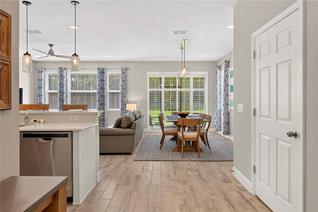 A kitchen island with a dishwasher faces an open dining area and living room — 15190 SUNRISE GROVE CT, WINTER GARDEN, FL