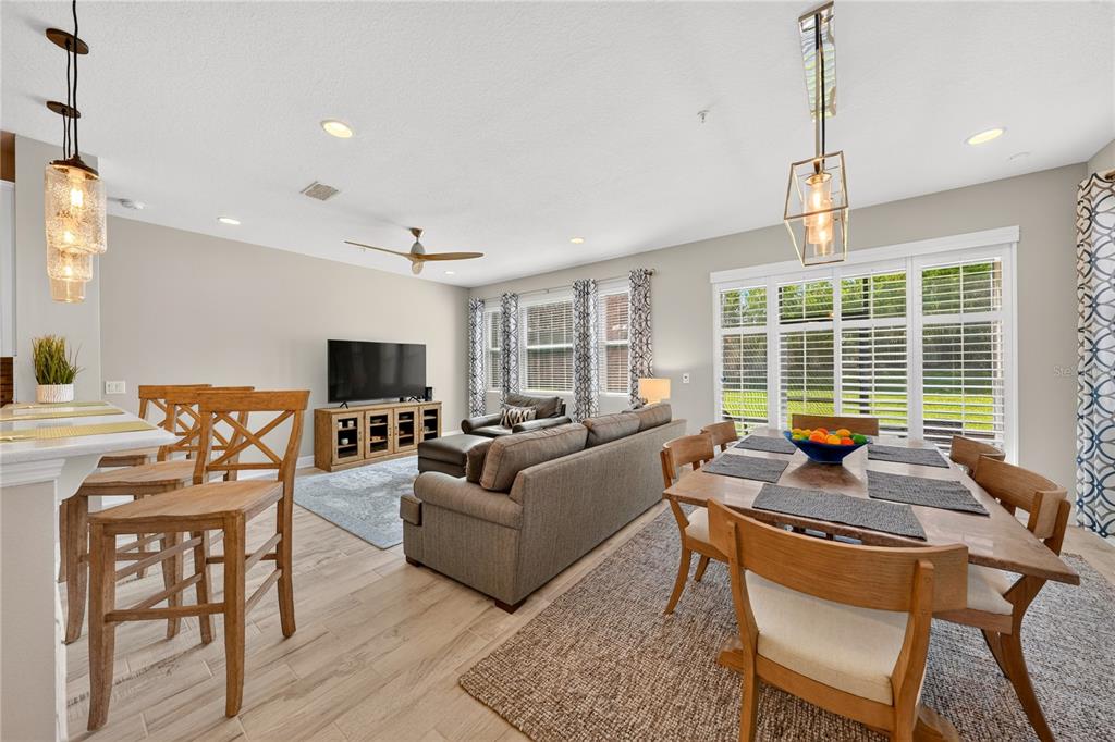An open-concept living and dining area features light wood flooring, neutral walls, and modern lighting — 15190 SUNRISE GROVE CT, WINTER GARDEN, FL