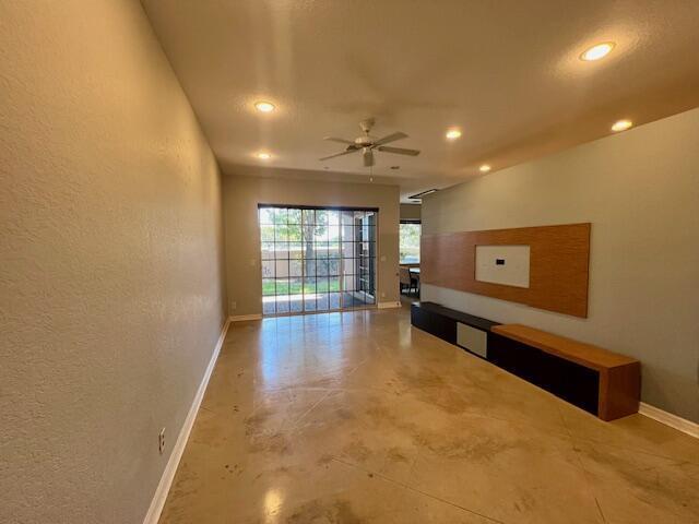 A living room with polished concrete floors, a ceiling fan, and a wood-paneled media wall — 30 Beechdale Lane, Boynton Beach FL 33426, BOYNTON BEACH, FL