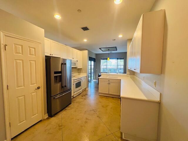 A kitchen features white cabinetry, stainless steel appliances, and light-colored concrete flooring — 30 Beechdale Lane, Boynton Beach FL 33426, BOYNTON BEACH, FL