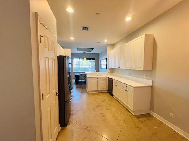 A kitchen features white cabinets, stainless steel appliances, and stained concrete floors — 30 Beechdale Lane, Boynton Beach FL 33426, BOYNTON BEACH, FL