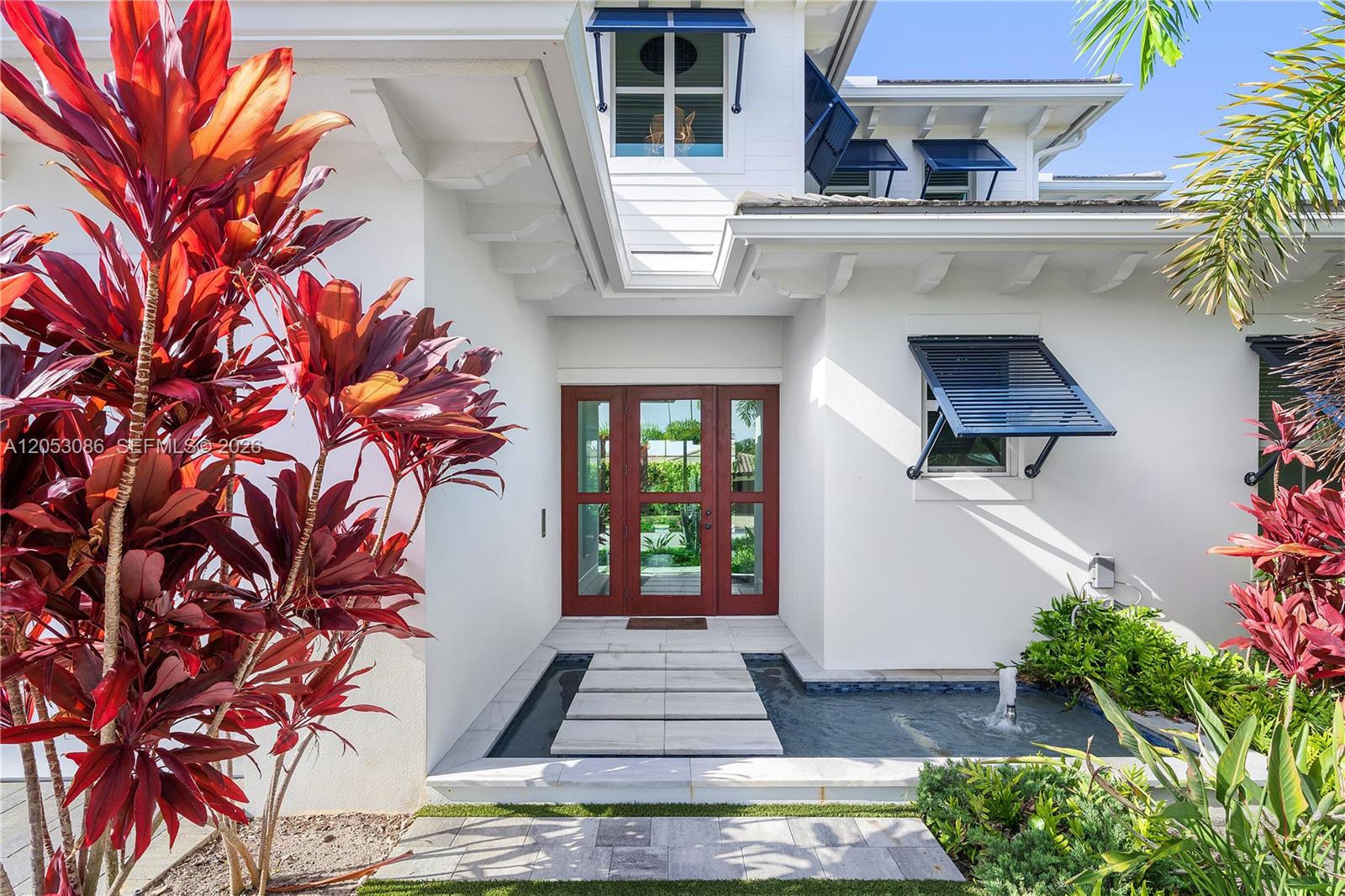 A white house exterior features a front door accessed by stone pavers over a pond — 728 Malaga Dr, Boca Raton FL 33432, BOCA RATON, FL