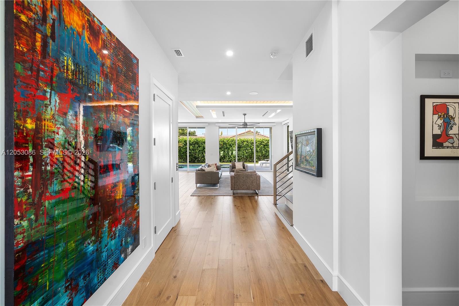 A hallway with wood floors leads to a living room overlooking a backyard pool — 728 Malaga Dr, Boca Raton FL 33432, BOCA RATON, FL