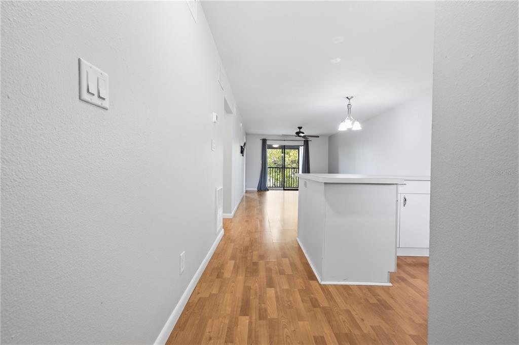 A view from a hallway looking toward a kitchen island and a balcony with trees — 6033 34TH STREET W UNIT 44, BRADENTON, FL