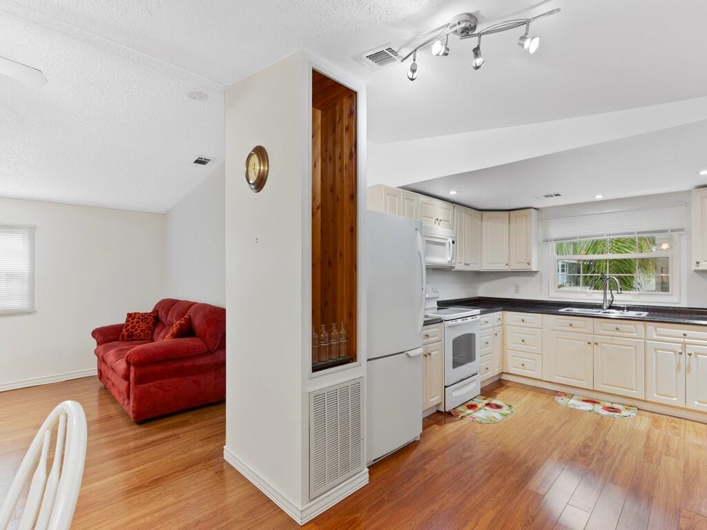 A kitchen with white cabinets and a wood-paneled divider wall next to a living area — 471 Tropical Isles Circle, Fort Pierce FL 34982, FORT PIERCE, FL