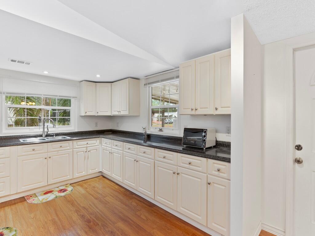A kitchen with cream-colored cabinets, dark countertops, and light wood flooring — 471 Tropical Isles Circle, Fort Pierce FL 34982, FORT PIERCE, FL