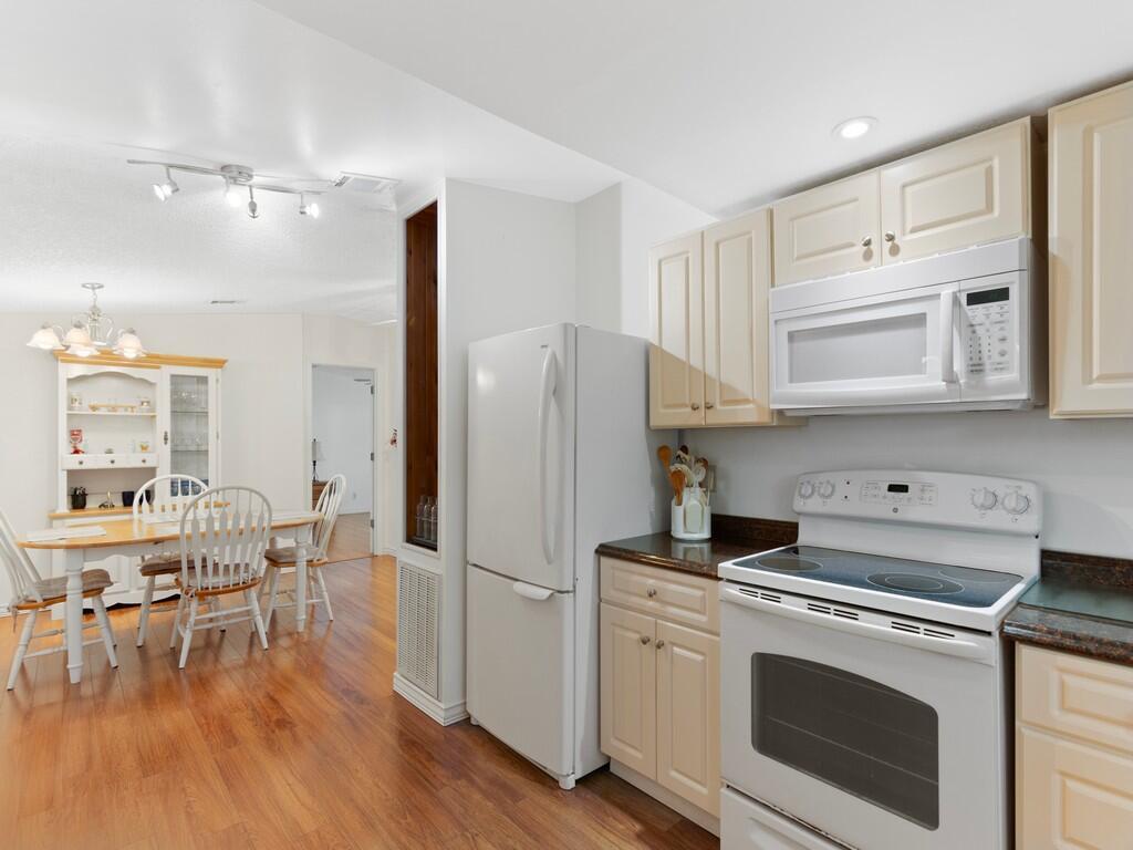 A kitchen with white appliances and light-colored cabinets opens into a dining area — 471 Tropical Isles Circle, Fort Pierce FL 34982, FORT PIERCE, FL