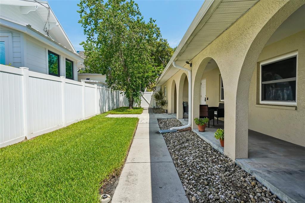 A side yard features a concrete walkway, a grassy lawn, and a covered arched patio — 144 8TH AVENUE N, ST PETERSBURG, FL