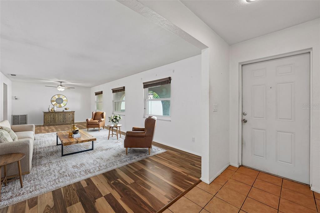 A living room features wood flooring, a large area rug, and a white front door — 144 8TH AVENUE N, ST PETERSBURG, FL