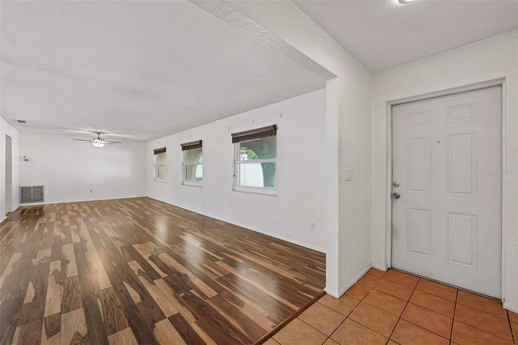 An interior view shows a living area with wood-look flooring, white walls, and a tiled entryway — 144 8TH AVENUE N, ST PETERSBURG, FL