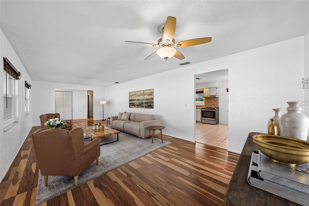 A living room with wood flooring, a ceiling fan, leather armchairs, and a beige sofa — 144 8TH AVENUE N, ST PETERSBURG, FL