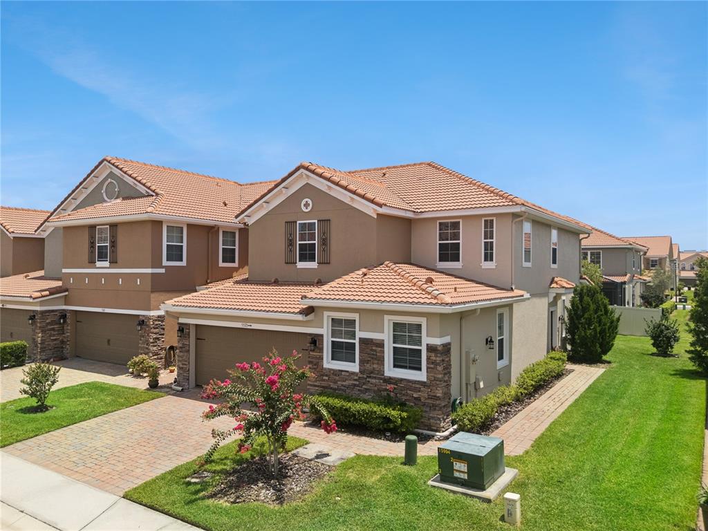An exterior view of a two-story stucco house with a tile roof and stone accents — 5571 SIRACUSA LANE, SANFORD, FL