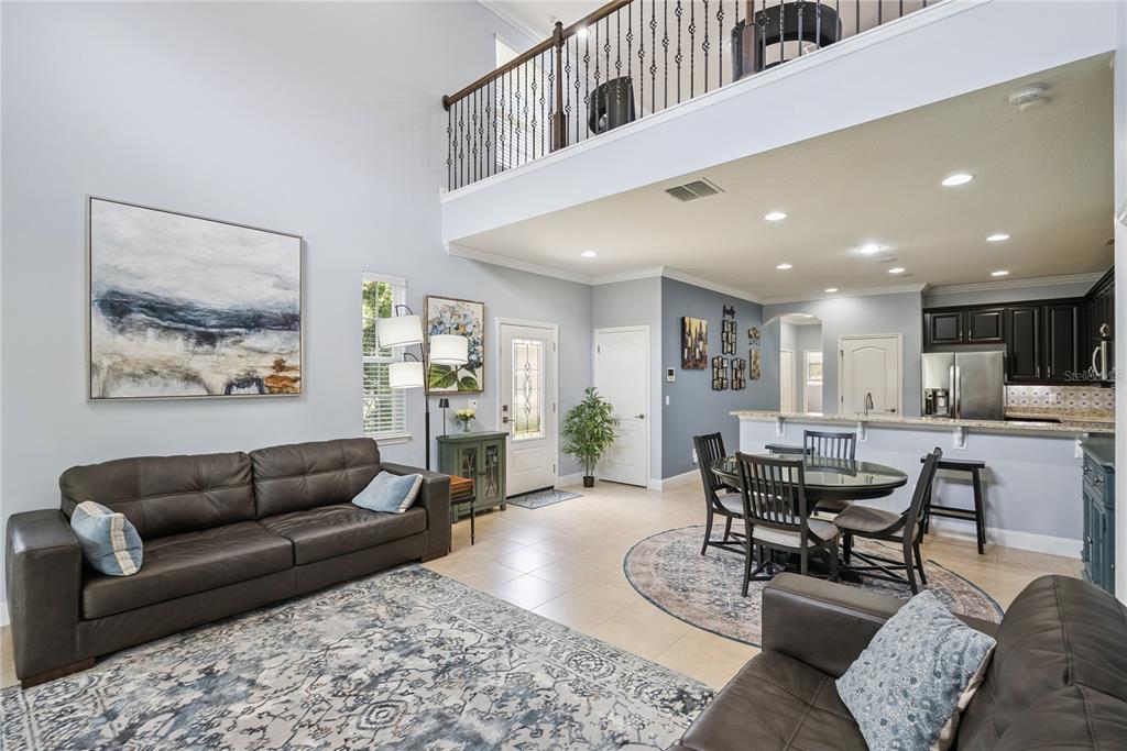 A living room and dining area with high ceilings, tile floors, and dark leather furniture — 5571 SIRACUSA LANE, SANFORD, FL