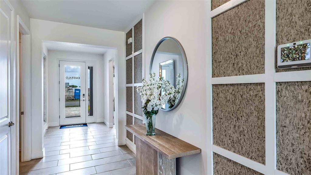 A bright entryway features a wood console table, a round mirror, and textured wall panels — 18245 GANDER TERRACE, LAKEWOOD RANCH, FL