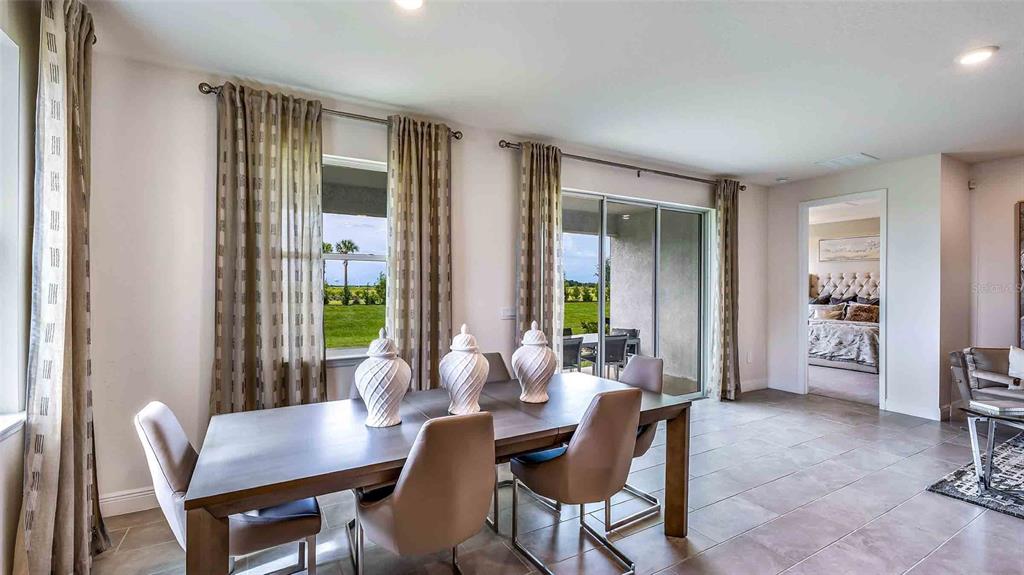 A dining room with a wooden table, chairs, and sliding glass doors leading to a patio — 18245 GANDER TERRACE, LAKEWOOD RANCH, FL
