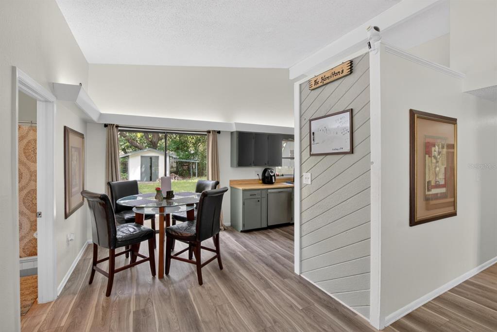 A bright, empty room features light-colored walls, wood-look flooring, a vaulted ceiling, and sliding doors — 113 6TH JPV STREET, WINTER HAVEN, FL