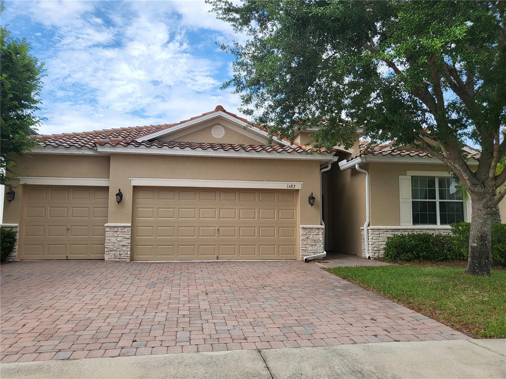 A single-story house with a tan stucco exterior, tile roof, and a three-car garage — 1482 LAKE SIDE AVENUE, DAVENPORT, FL