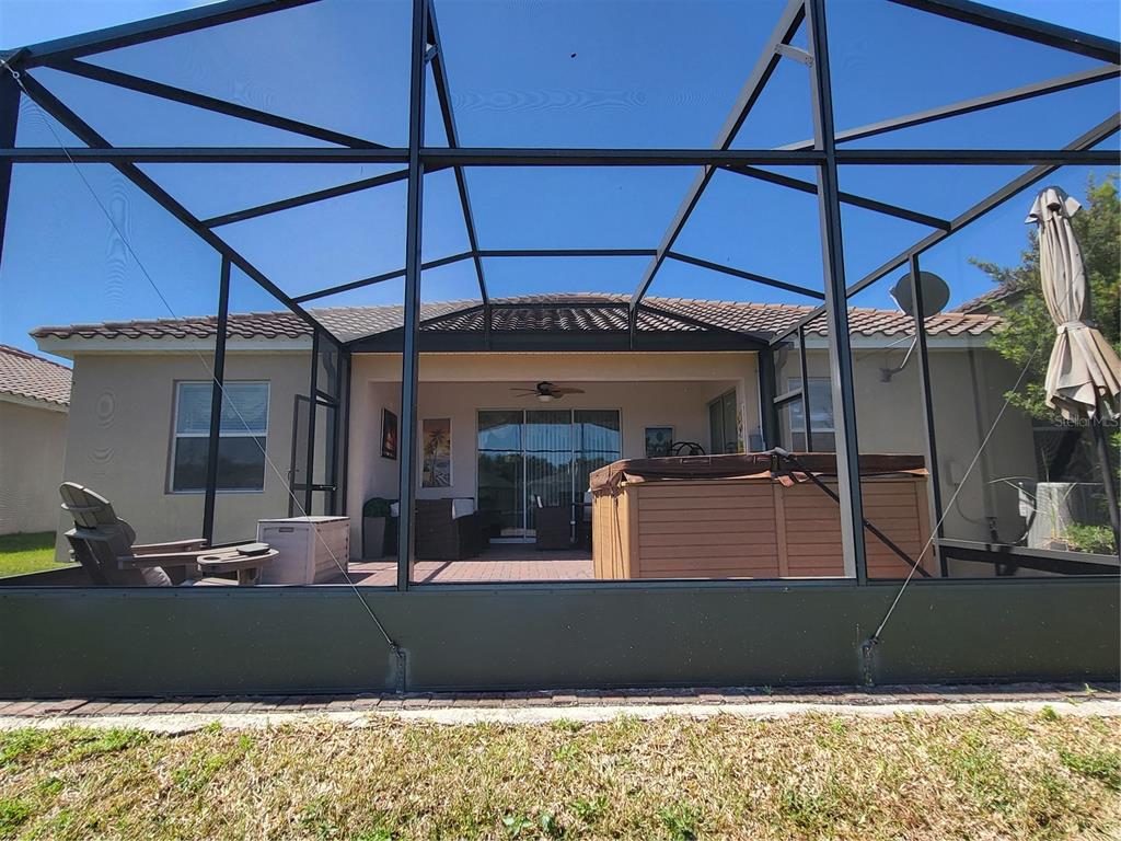 A covered patio with a hot tub is enclosed by a black metal screen structure — 1482 LAKE SIDE AVENUE, DAVENPORT, FL