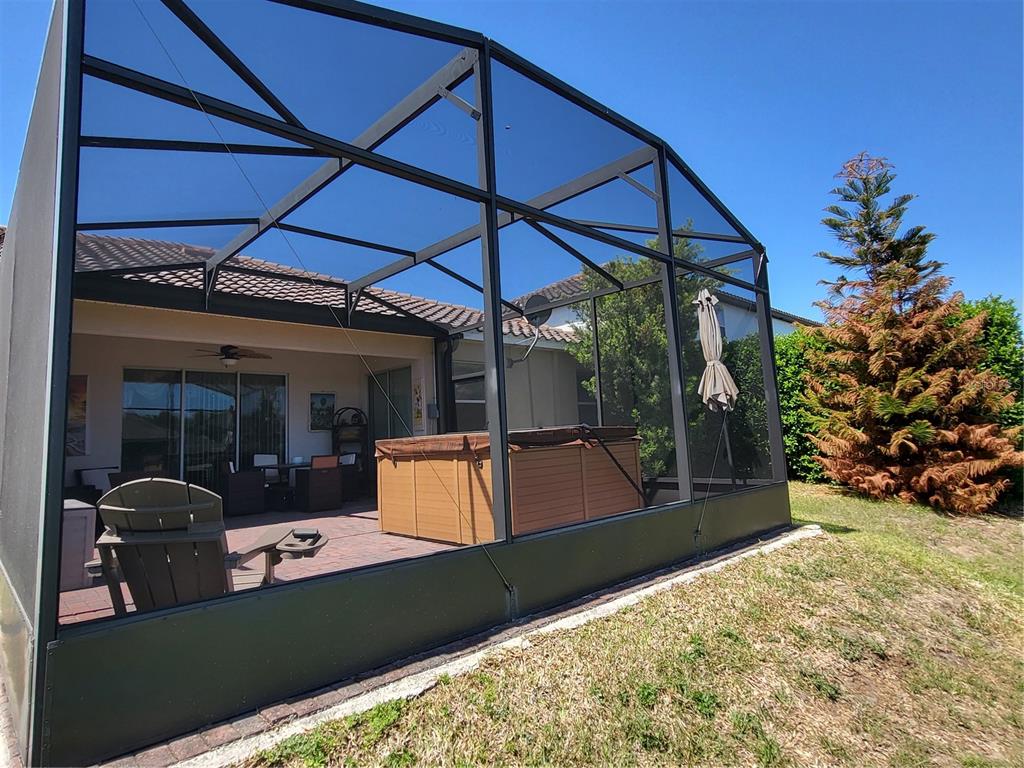 A screened-in patio features a hot tub, outdoor furniture, and a view of the yard — 1482 LAKE SIDE AVENUE, DAVENPORT, FL
