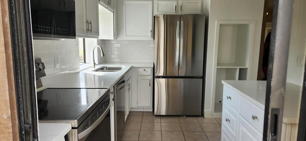 A kitchen features white cabinets, stainless steel appliances, subway tile backsplash, and tile flooring — 3466 BEEKMAN PLACE UNIT 36, SARASOTA, FL