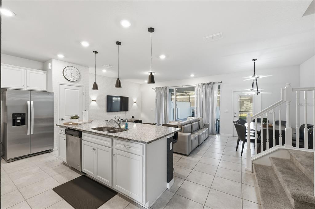 A kitchen with a granite island and stainless steel appliances opens to a living area — 236 JETTY WAY, DAVENPORT, FL