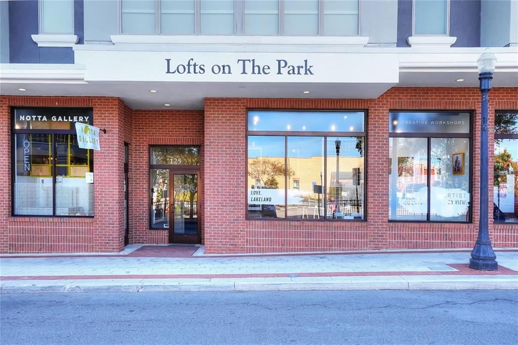 The exterior of a brick building features a storefront entrance labeled Lofts on The Park — 125 N KENTUCKY AVENUE UNIT 203, LAKELAND, FL