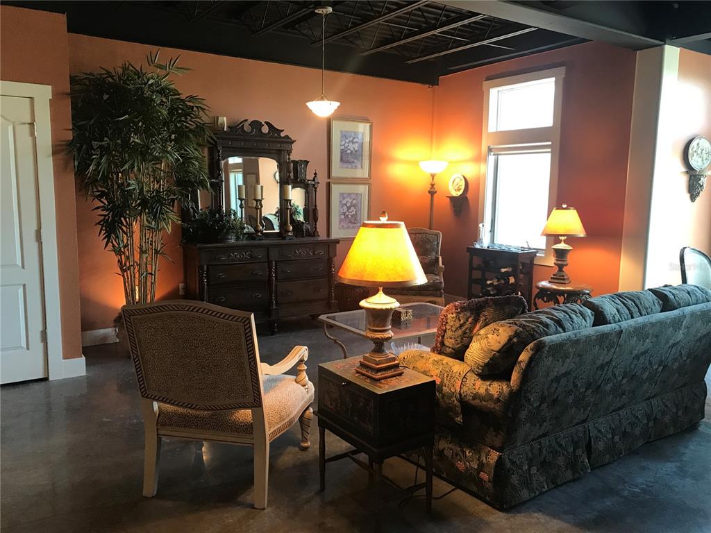 A living room features terracotta walls, a dark industrial ceiling, and traditional furniture — 125 N KENTUCKY AVENUE UNIT 203, LAKELAND, FL