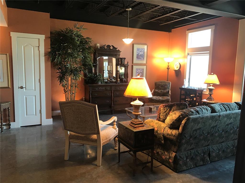 A living room features orange walls, a black exposed ceiling, and a concrete floor — 125 N KENTUCKY AVENUE UNIT 203, LAKELAND, FL