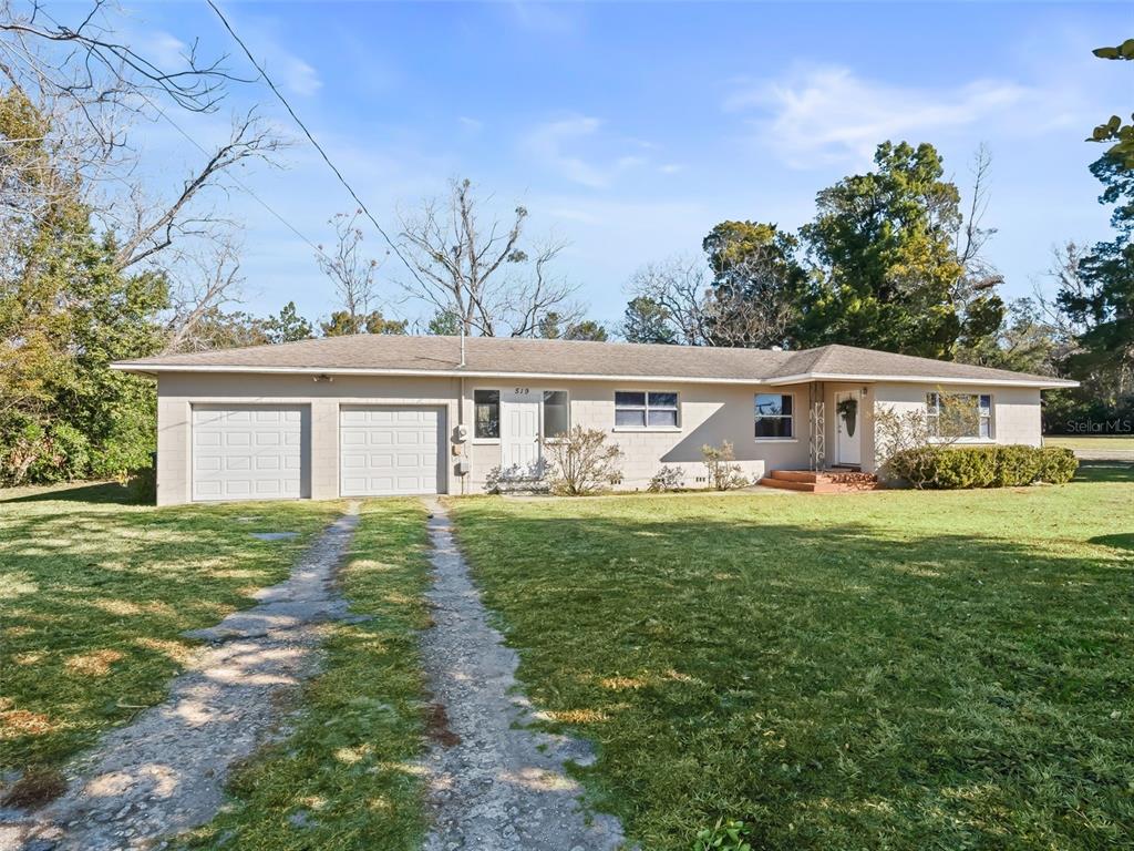 A single-story house with a two-car garage, a concrete driveway, and a large front lawn — 519 HUEY STREET, WILDWOOD, FL