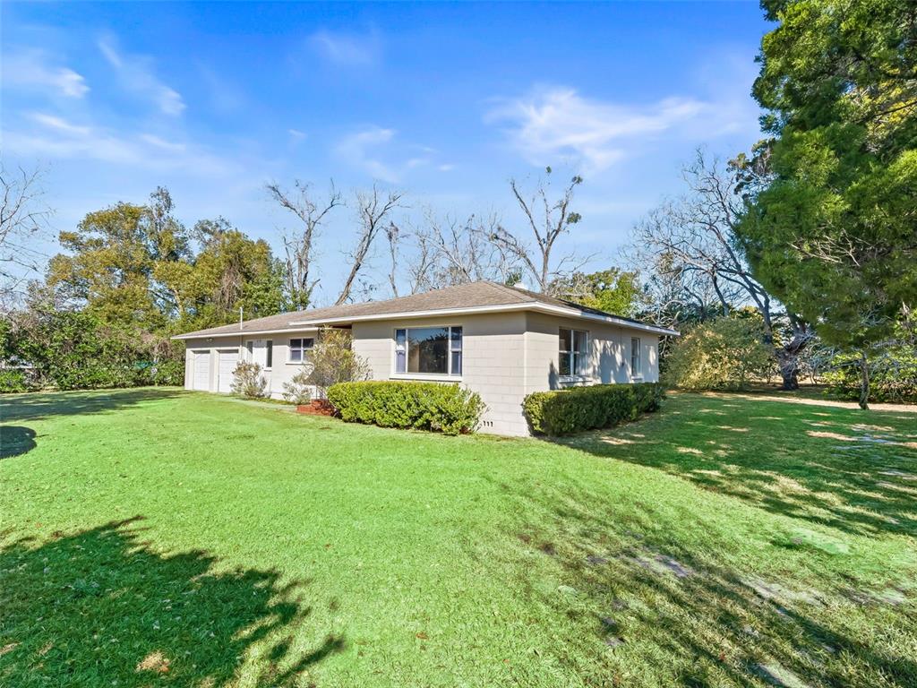 A single-story concrete block house with a hip roof sits on a large grassy lot — 519 HUEY STREET, WILDWOOD, FL