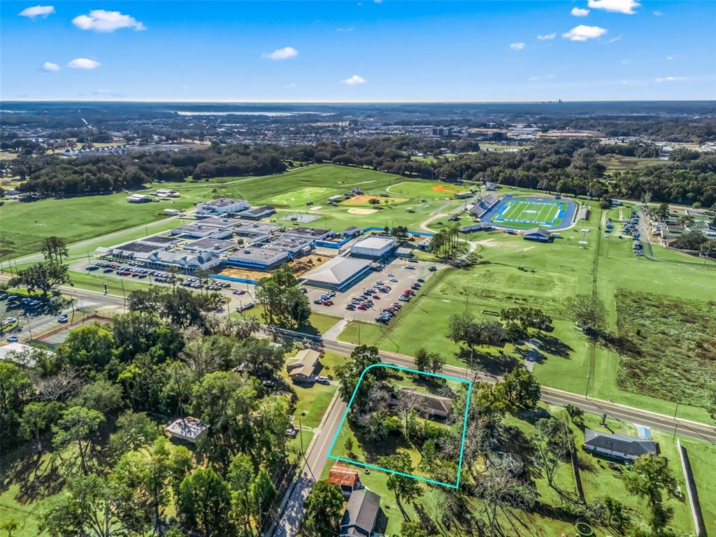 An aerial view shows a house outlined in blue near a large school campus — 519 HUEY STREET, WILDWOOD, FL