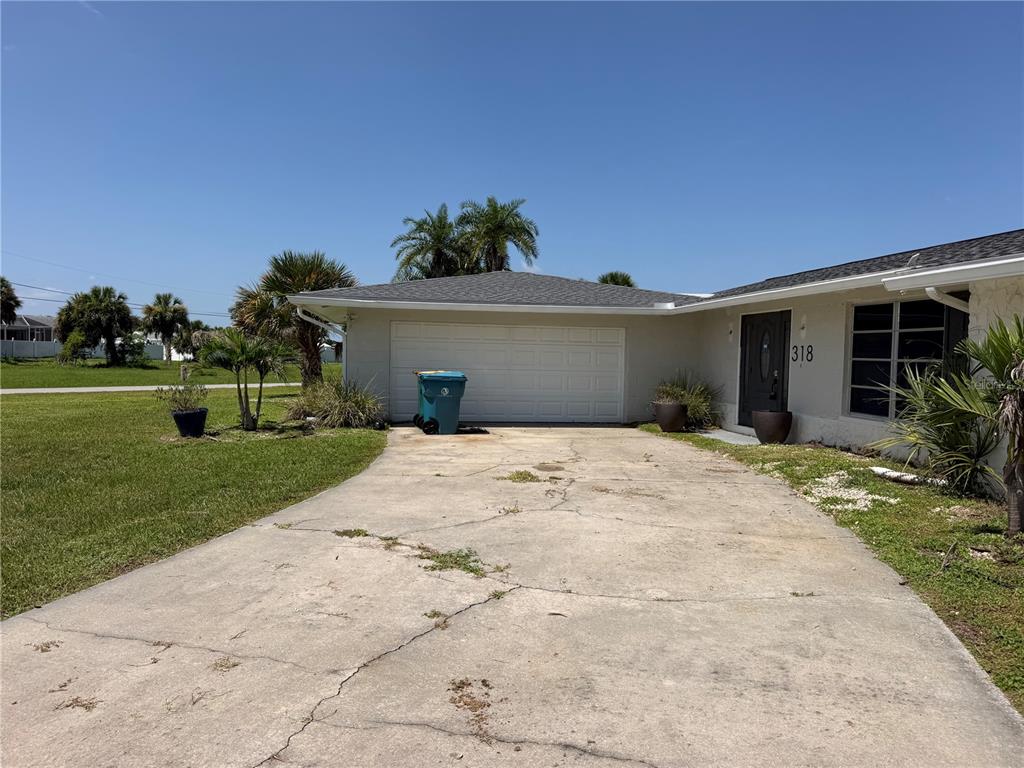 A concrete driveway leads to a one-car garage and the front entrance of a house — 318 SKYLARK LANE NW, PORT CHARLOTTE, FL