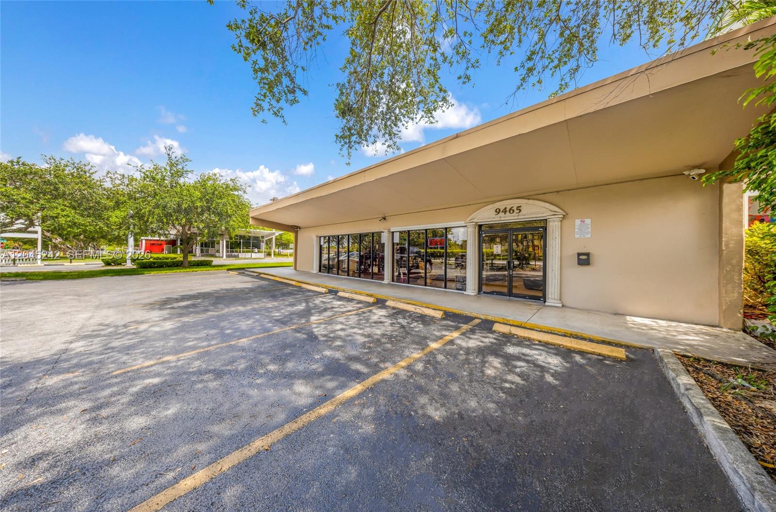 A commercial building exterior features a glass storefront, a tan overhang, and a paved parking lot — 9465 SW 56th St, Miami FL 33165, MIAMI, FL
