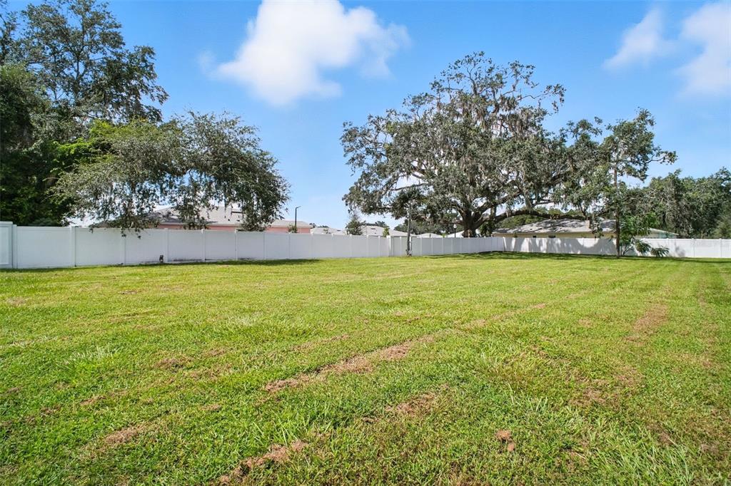 A large, grassy vacant lot is enclosed by a white vinyl privacy fence — 12182 N US HIGHWAY 301, OXFORD, FL
