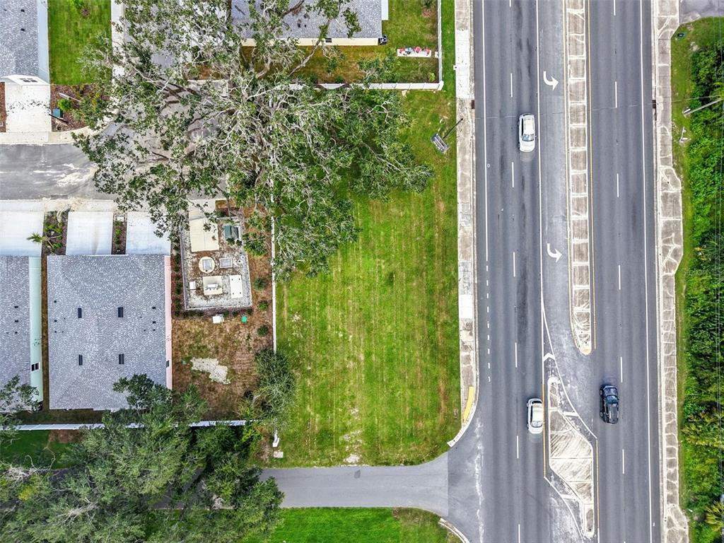 An aerial view shows a vacant grassy lot situated between a residential building and a road — 12182 N US HIGHWAY 301, OXFORD, FL
