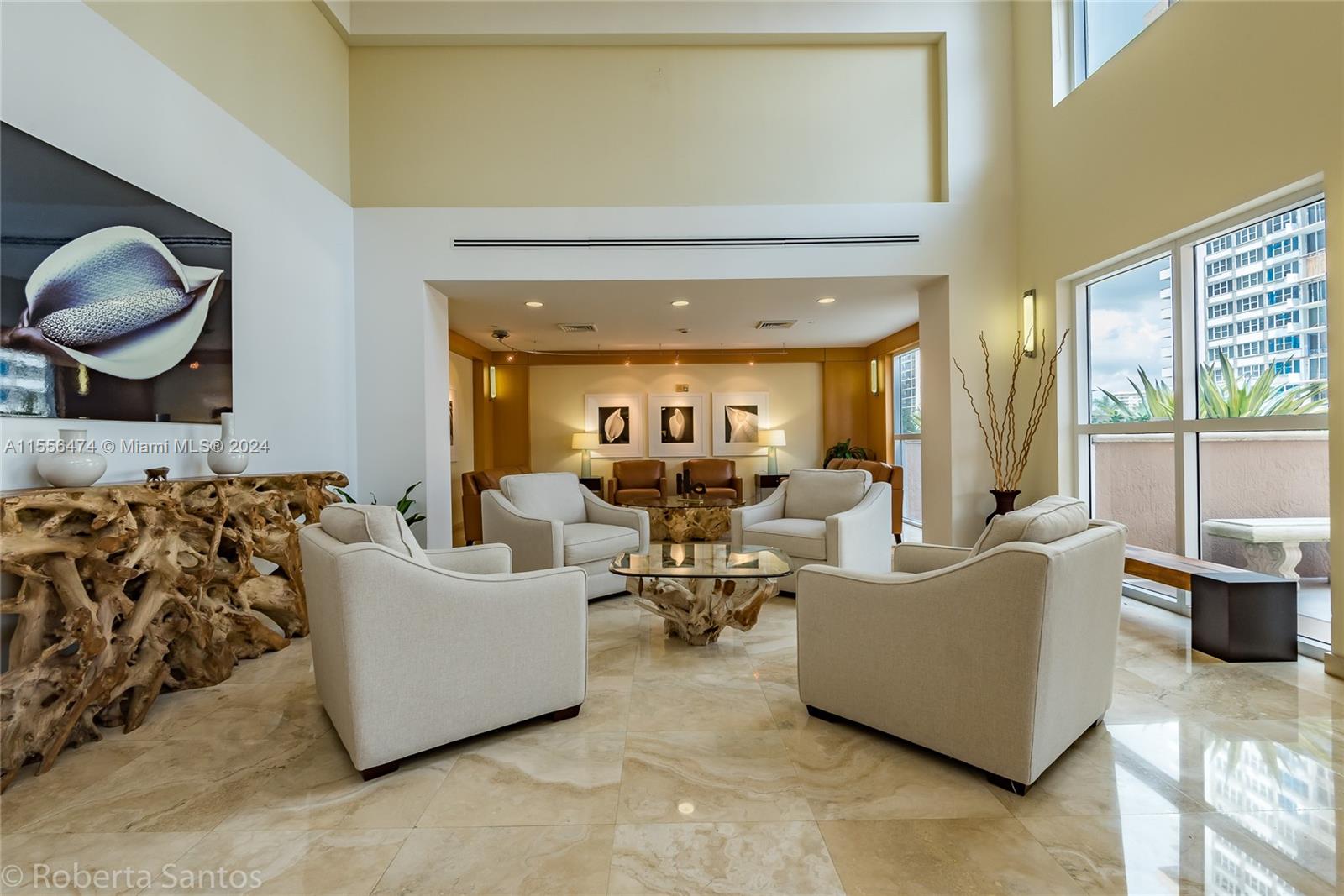 A spacious lobby features four cream armchairs, a glass-topped driftwood coffee table, and marble flooring — 2080 S Ocean Dr # 602, Hallandale Beach FL 33009, HALLANDALE BEACH, FL