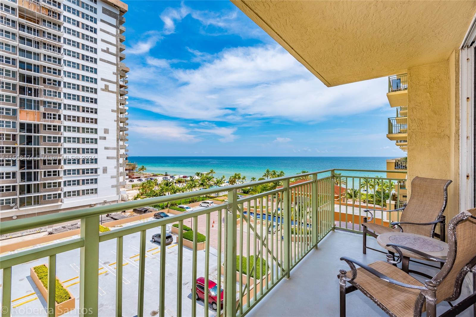 A balcony with two chairs overlooks a parking lot, a neighboring high-rise, and the ocean — 2080 S Ocean Dr # 602, Hallandale Beach FL 33009, HALLANDALE BEACH, FL