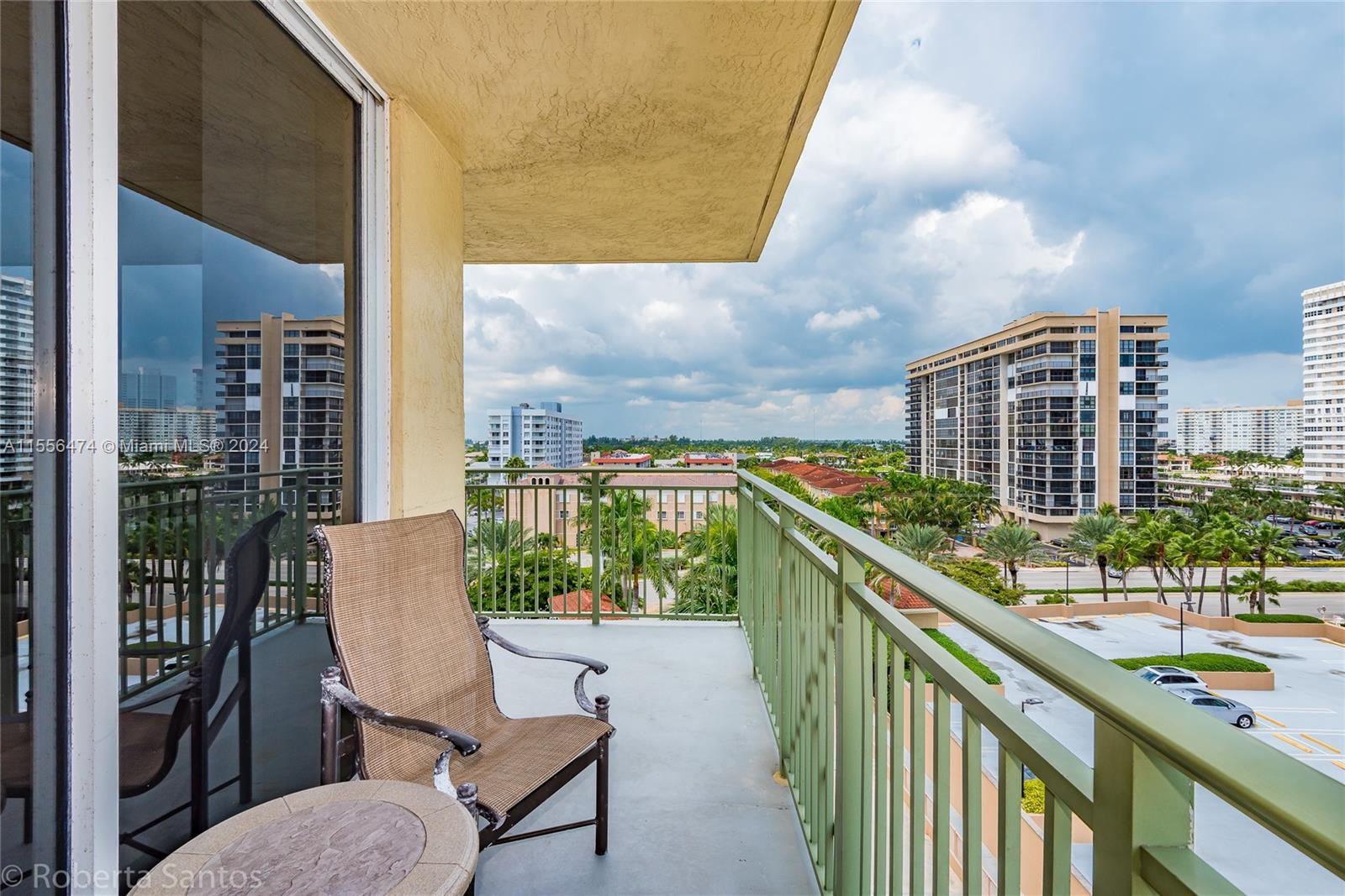 A balcony with a chair and table overlooks a parking lot and city buildings — 2080 S Ocean Dr # 602, Hallandale Beach FL 33009, HALLANDALE BEACH, FL