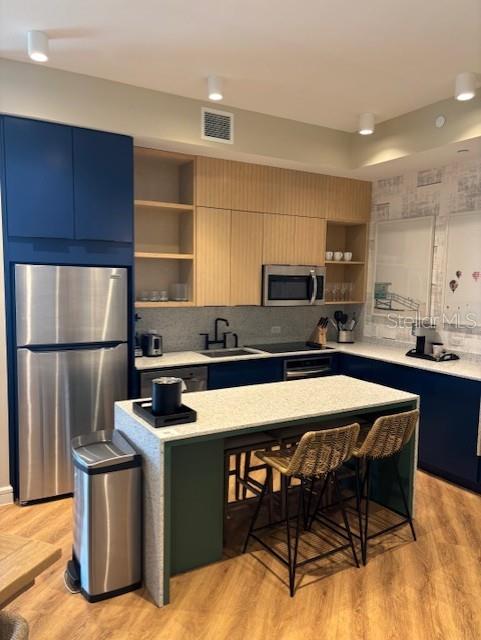 A modern kitchen features blue and light wood cabinetry, a stone island, and stainless appliances — 3151 SUNSET WALK DR UNIT 1104, KISSIMMEE, FL