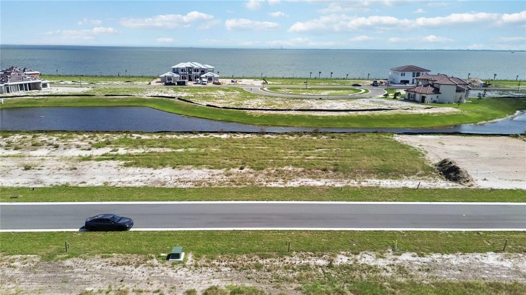 An aerial view shows a vacant residential lot near a pond and a large body of water — 6123 SOLSTICE DRIVE, TITUSVILLE, FL