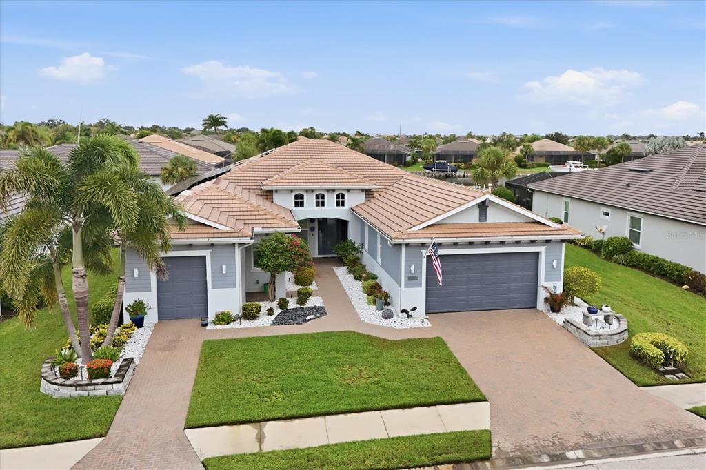 An aerial view of a single-story house with a tile roof, two garages, and landscaping — 5609 TIDEWATER PRESERVE BOULEVARD, BRADENTON, FL