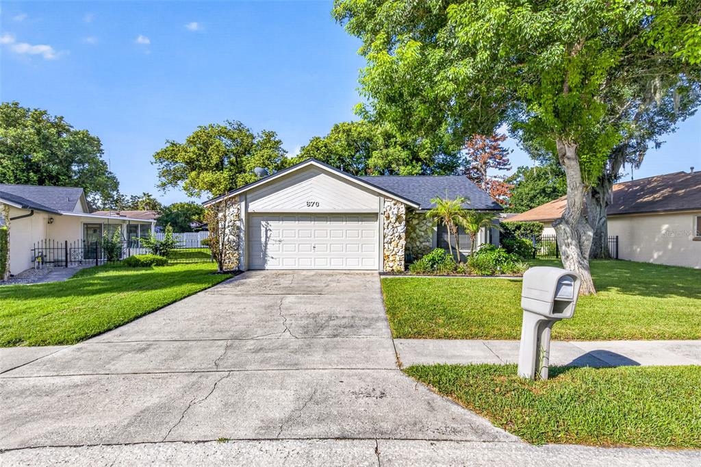 A single-story house with a stone facade, a two-car garage, and a concrete driveway — 670 STANHOPE DRIVE, CASSELBERRY, FL
