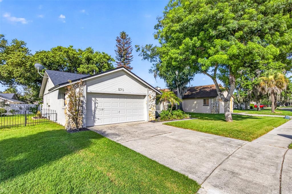 A single-story house with a white garage door, stone accents, and a green lawn — 670 STANHOPE DRIVE, CASSELBERRY, FL