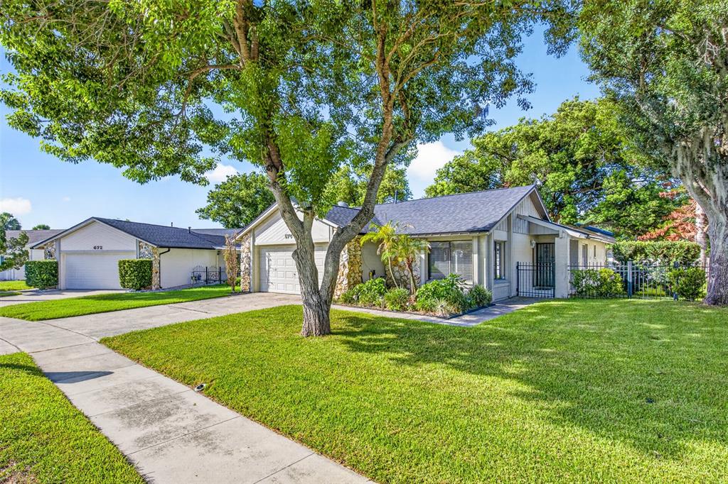 A single-story house with a stone facade, a concrete driveway, and a large shade tree — 670 STANHOPE DRIVE, CASSELBERRY, FL