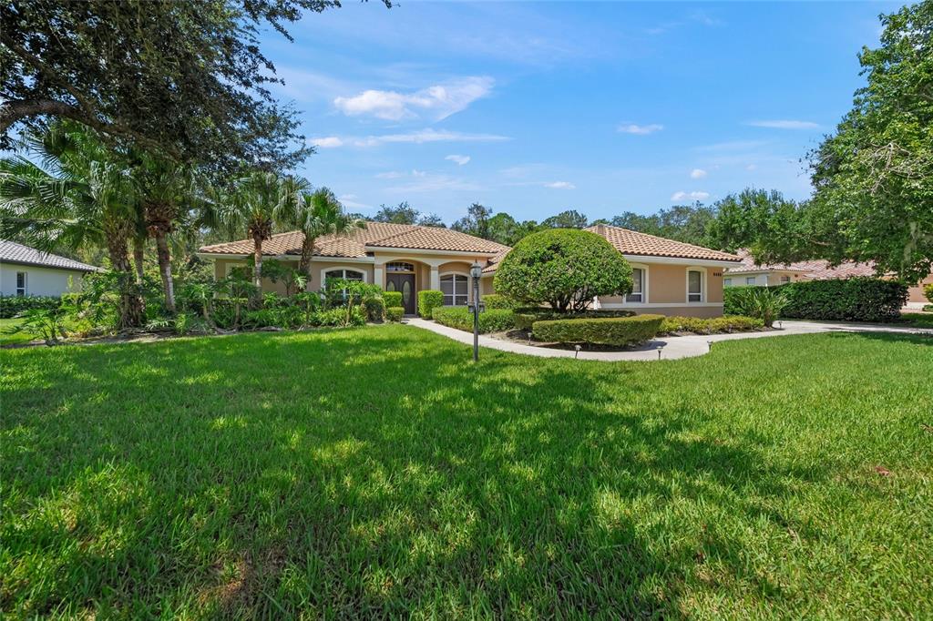 A single-story house with a tile roof, arched entryway, and landscaped front lawn — 8488 EAGLE PRESERVE WAY, SARASOTA, FL